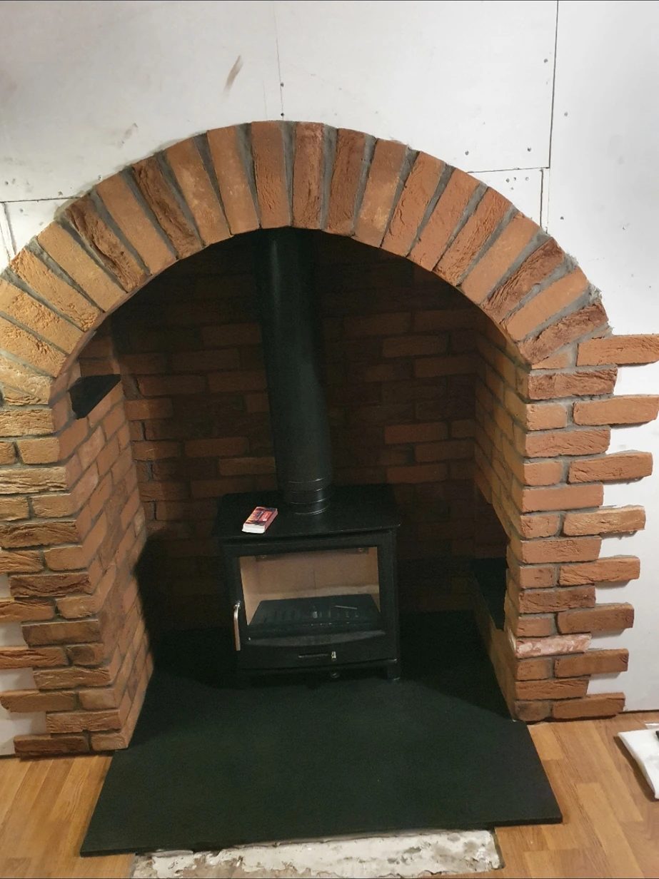 Multi fuel stove set into brick arch inglenook